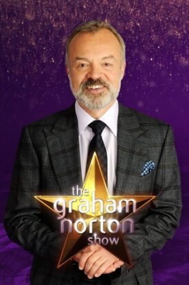 A man in a suit holding a sign for the Graham Norton Show with a purple starry background.